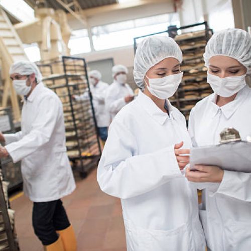 Women working at a food factory and looking at checklist on a clipboard